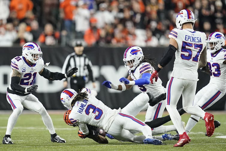 A player wearing the number 3 falling onto the field, surrounded by other players