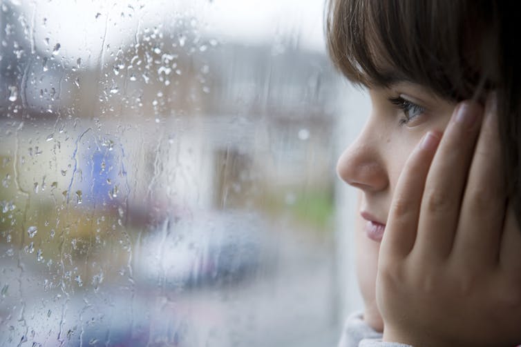 Sad young girl looking out of window