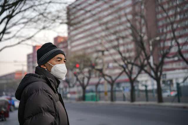 A man on a street in Beijing wearing a mask.