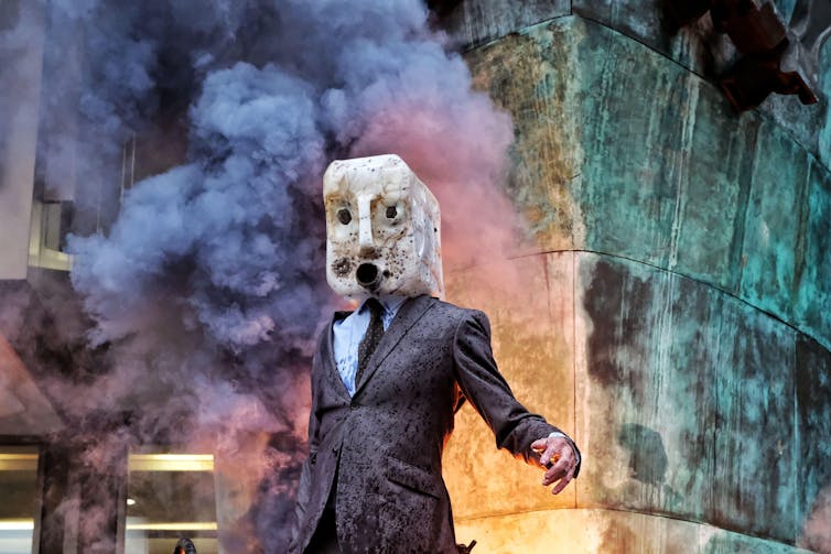 Man in mask in front of colourful smoke