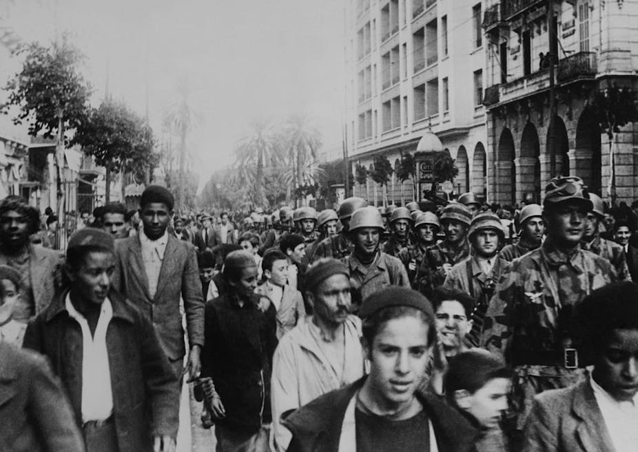 Photo en noir et blanc montrant une rue de Tunis où des soldats allemands marchent parmi  une foule locale