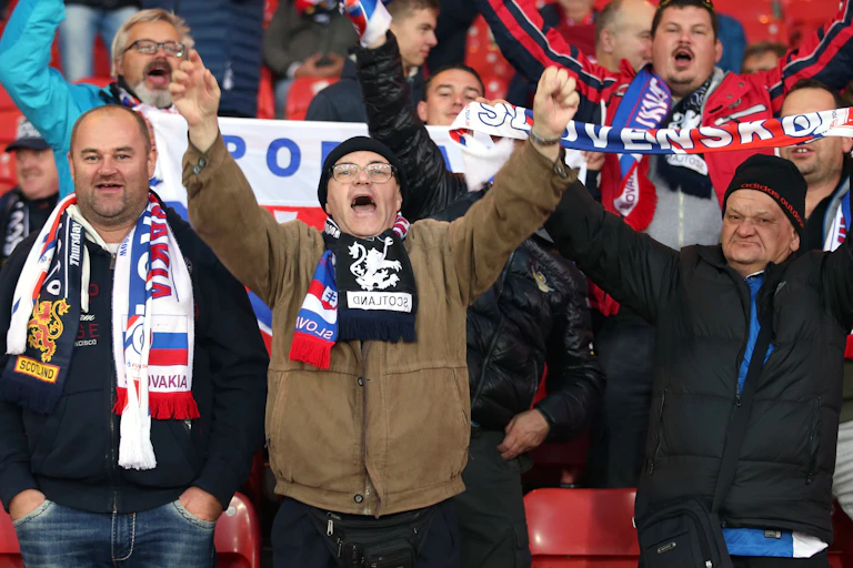 Older men hold aloft scarfs with Scottish and Slovakian emblems and slogans.