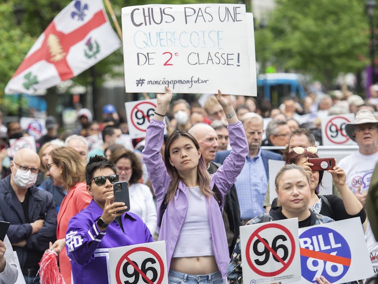 People at a protest carry signs featuring the number 96 with a red line across it.