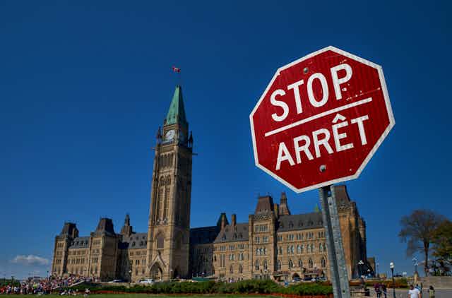 A stop sign in english and french in front of the Canadian parliament building