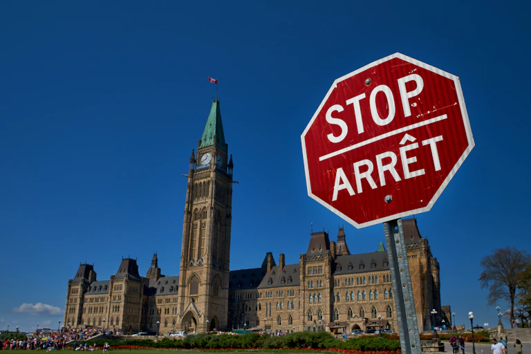 A stop sign in english and french in front of the Canadian parliament building