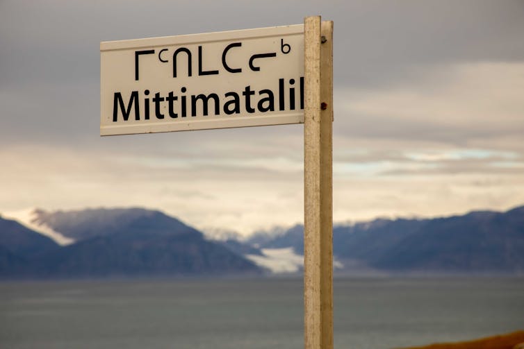 A white street sign in the English and Inuit languages that reads: Mittimatalil.