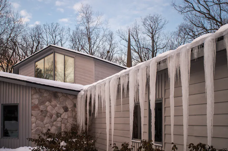 A house roof riddled with icicles.