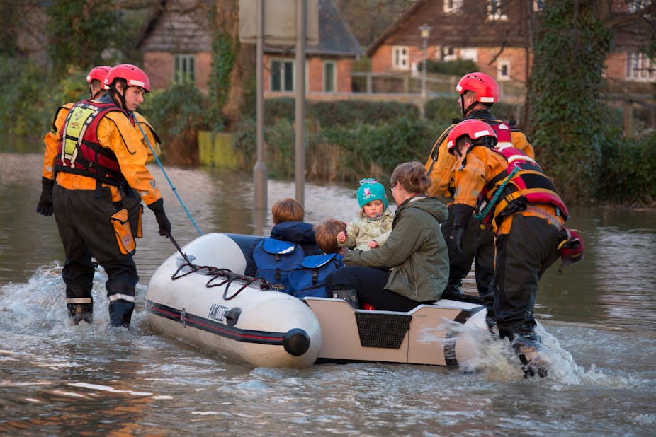 A family being rescued from flood waters in a small boat.