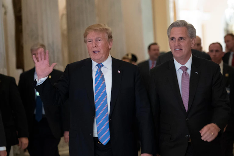 Two men one on a blue tie and one in a red tie walking next to each other.