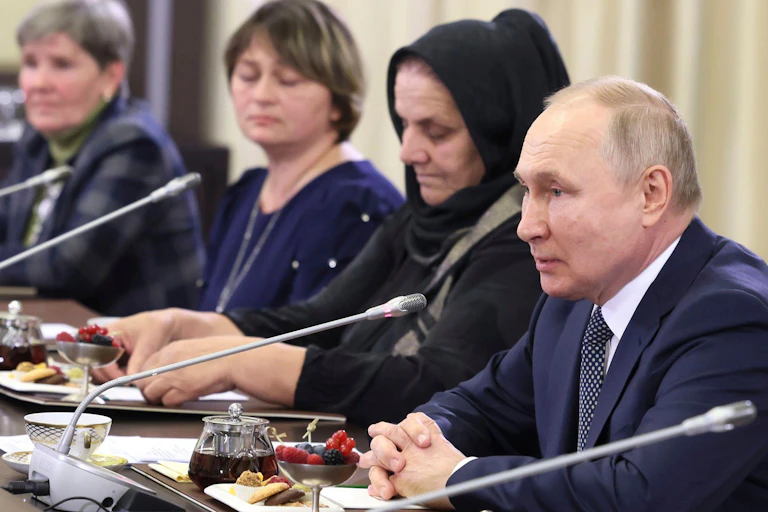 Women sitting in front of microphones next to President Putin.