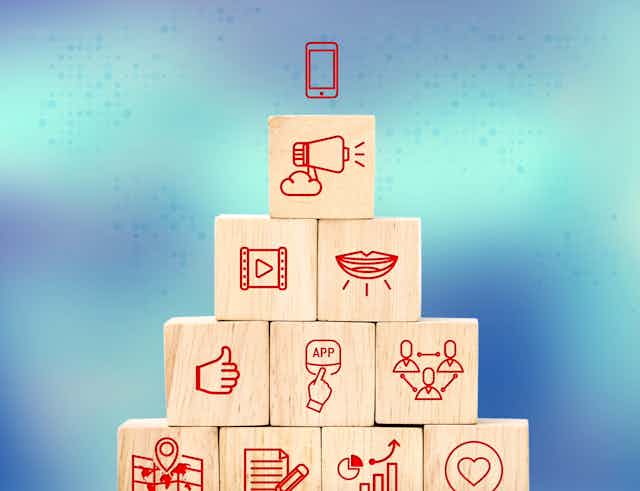 Wooden blocks stacked in a pyramid with icons representing actions carried out on the internet, such as liking, clicking and sharing. 