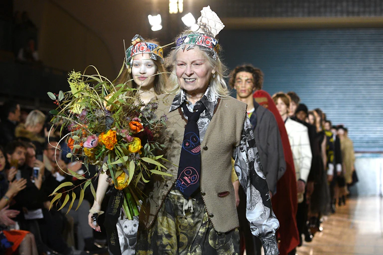 A woman and models walk down a catwalk.