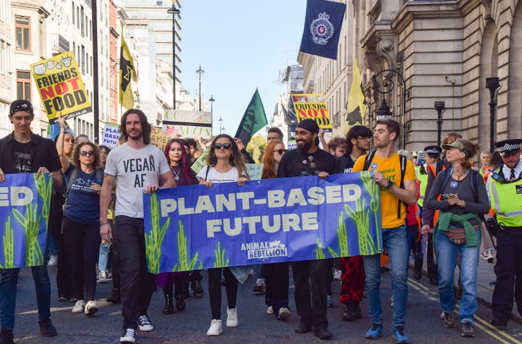Protestors marching behind a sign reading 'plant-based future'