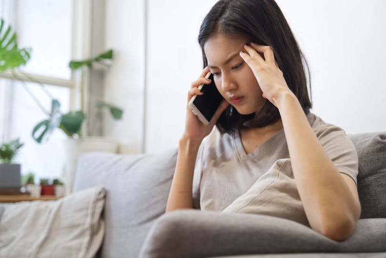 A woman at home on the phone, appears frustrated.