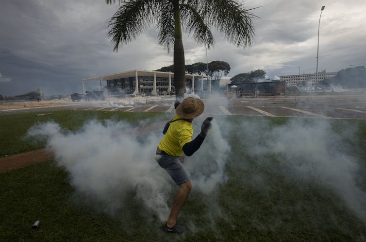 A protestor in a yellow top is surrounded by a cloud of smoke.