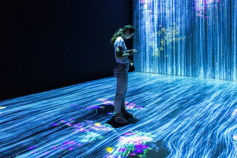 A person standing in a dark room with blue lines illuminating the floor and one wall