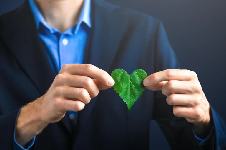 Hombre de negocios sostiene una hoja con forma de corazón.