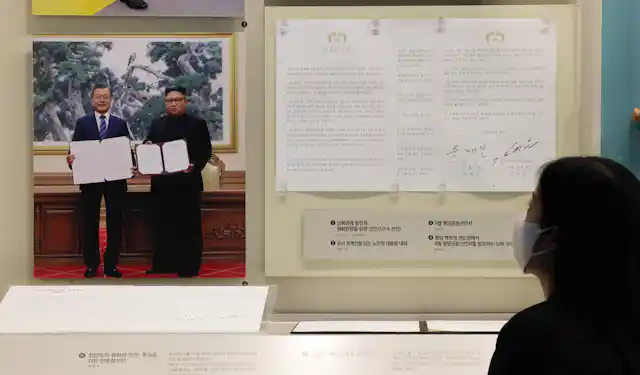 A woman reads the 2018 Pyongyang Joint Declaration displayed on a wall in Seoul with a picture of South Korean president, Moon Jae-in, and North Korean leader Kim Jong-un.