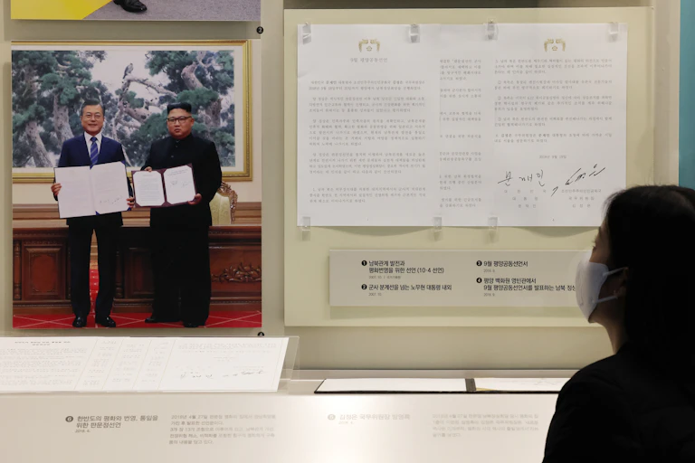 A woman reads the 2018 Pyongyang Joint Declaration displayed on a wall in Seoul with a picture of South Korean president, Moon Jae-in, and North Korean leader Kim Jong-un.