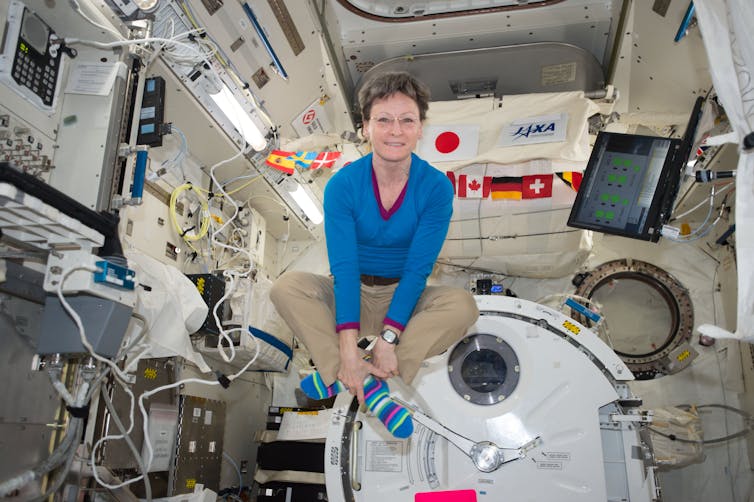 woman cross-legged floats inside a space module