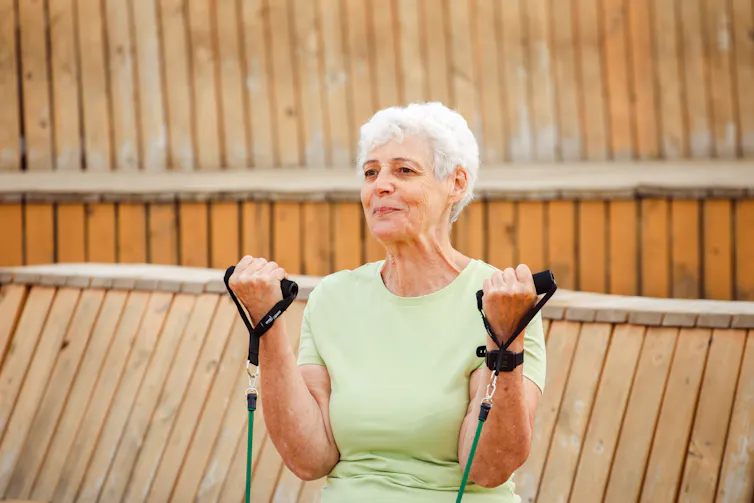 An older woman doing biceps curls with a resistance band
