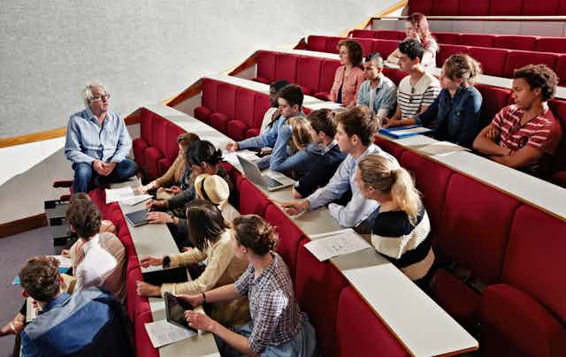 An academic teaching a small group of people in a university auditorium