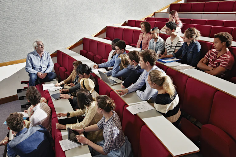 An academic teaching a small group of people in a university auditorium