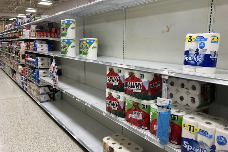 store shelves are seen partially empty with a small number of toilet paper rolls