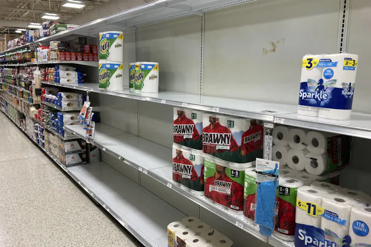 store shelves are seen partially empty with a small number of toilet paper rolls