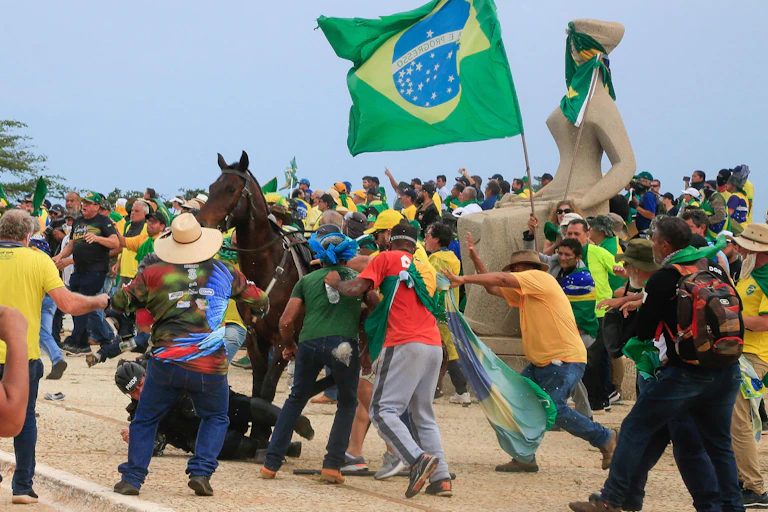 As some Brazilian flag-holding supporters of far-right ex-president Jair Bolsonaro charge him, a military police officer falls from his horse to the ground.