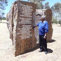 man looking at engraved large rock