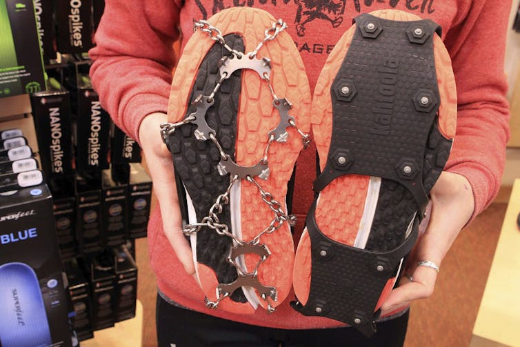 Image of the bottoms of a pair of shoes with orange soles, displaying two types of external ice cleats