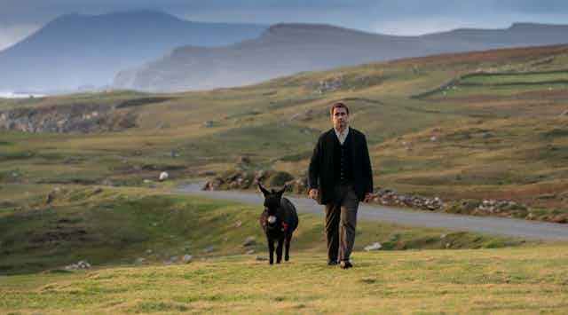 Pádraic (Colin Farrell) strides through dramatic Irish countryside with his companion, Jenny the little donkey.
