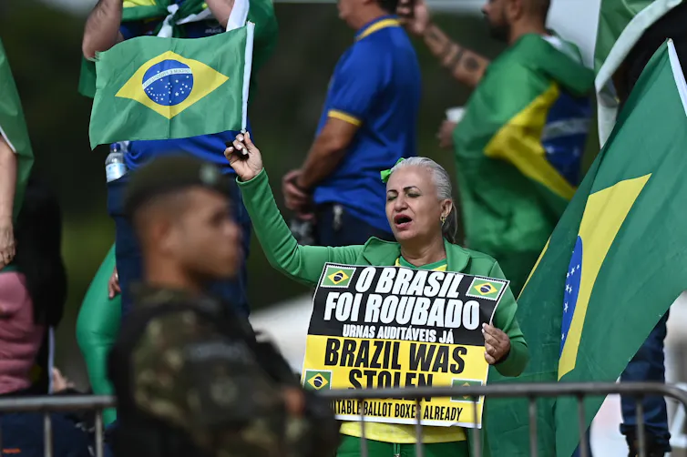 A protestor holds up a placard in Portuguese and English alleging that the 2022 presidential election was a fraud.