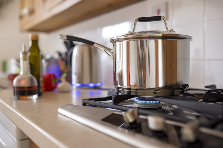 A pot sits over a gas-fired stove burner