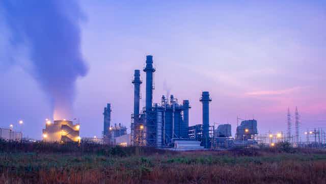 An industrial scene with cooling towers producing steam at dusk.