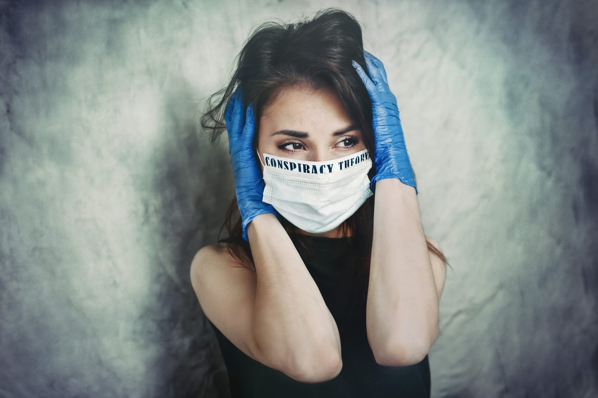 Terrified young woman in a medical mask and protective surgical sterile gloves