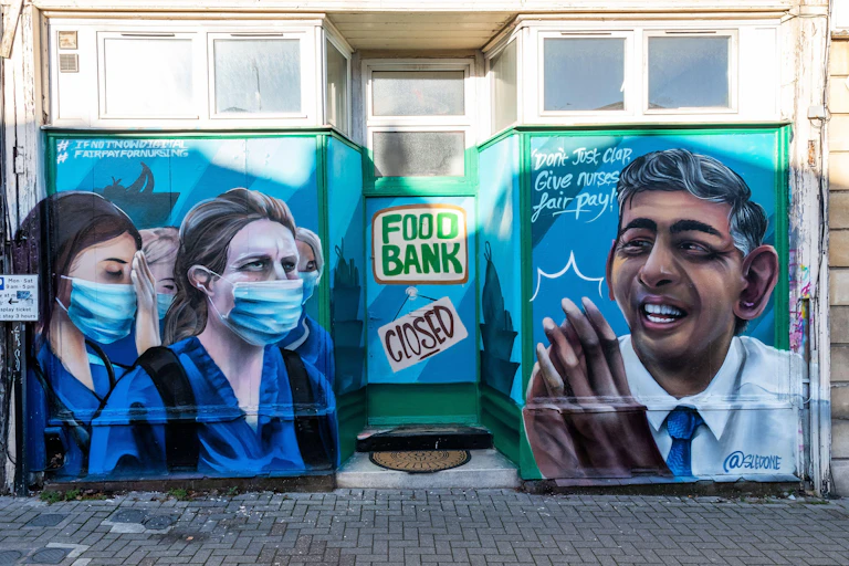 Graffiti depicts exhausted nurses, a closed food bank and a smiling Rishi Sunak under the words 'Don't just clap, give nurses fair pay!'