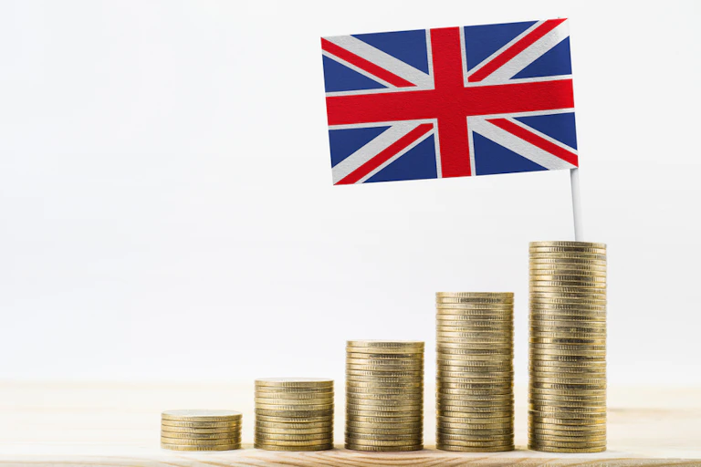 Stacks of gold coins (pound coins) growing with United kingdom flag (UK) on the largest, on a wooden shelf.