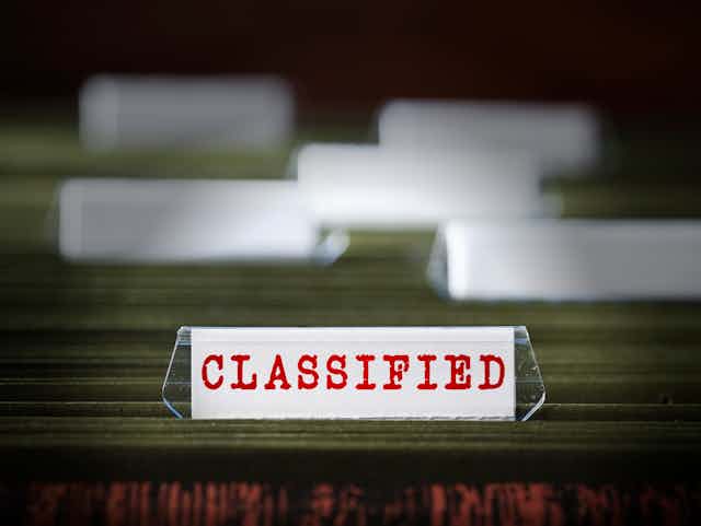A group of file folders, with one marked 'CLASSIFIED' in red