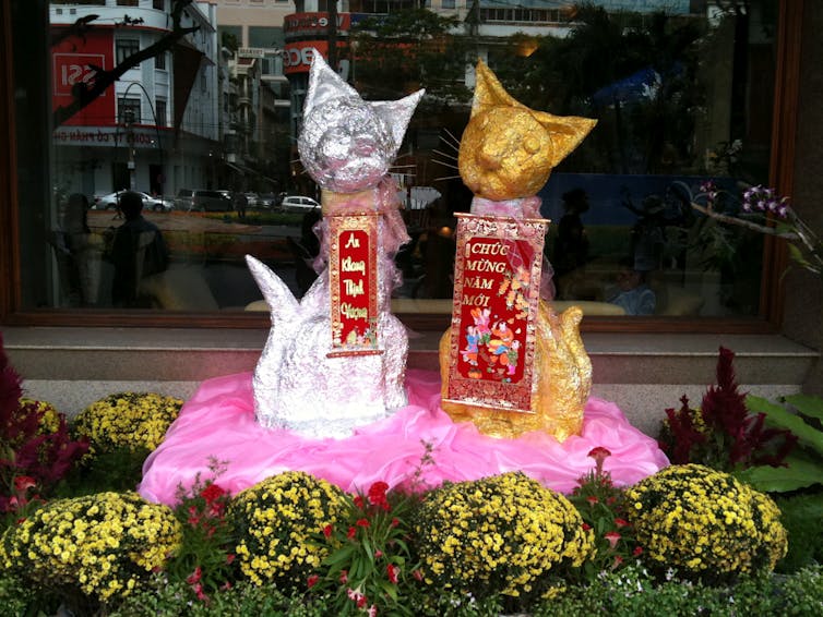 Two cat statues with red plaques covered in Vietnamese writing