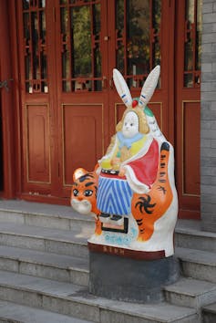 A statue of a figure with long rabbit ears sitting on a tiger