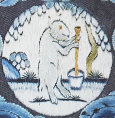 A rabbit stands on its hind legs and holds a long stick.