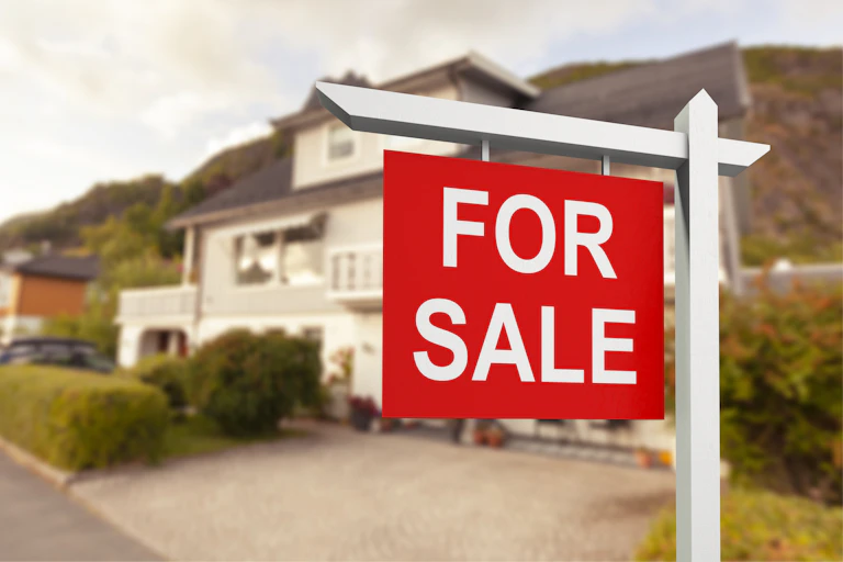 A for sale sign sitting outside a detached house