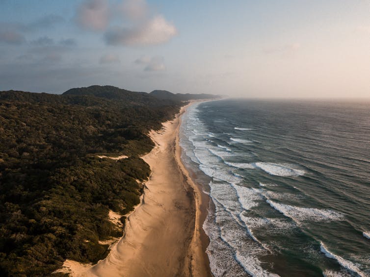 An aerial photo of waves crashing on a coastline.