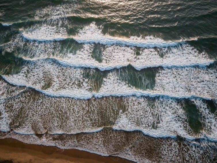 An aerial photo of waves rolling in to shore.