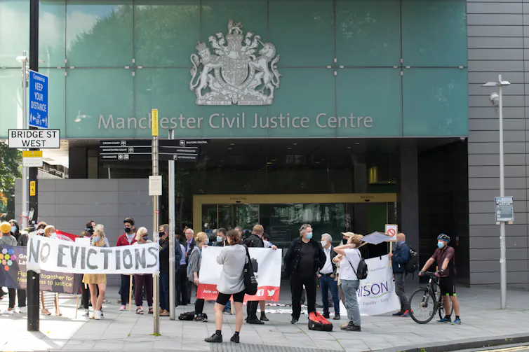 Protestors with banners in front of a court building.