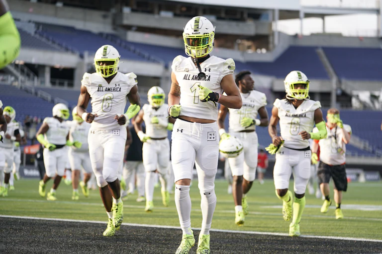 A group of football players jogs on a field.