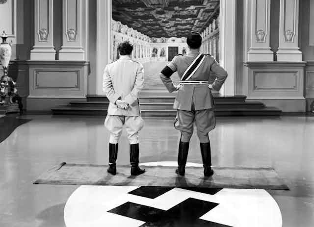 Dos hombres de uniforme de espaldas a la cámara miran al fondo de un pasillo.