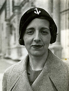 Una mujer con abrigo y sombrero mira a cámara.